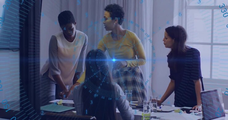 Pointing at chart four women collaborating on business plan with blue digital overlay fading