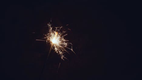 el fuego bengalí brilla en un fondo oscuro. las luces naranjas caen de todos lados. el concepto de vacaciones