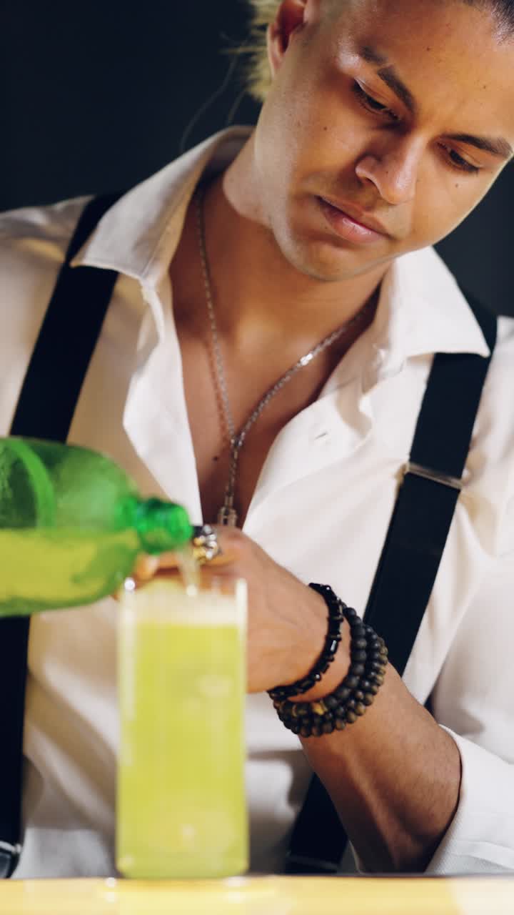 Barman che versa un cocktail verde in un bicchiere alto