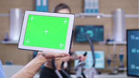 dolly toma de un doctor en ciencias del deporte sosteniendo una tableta con pantalla verde