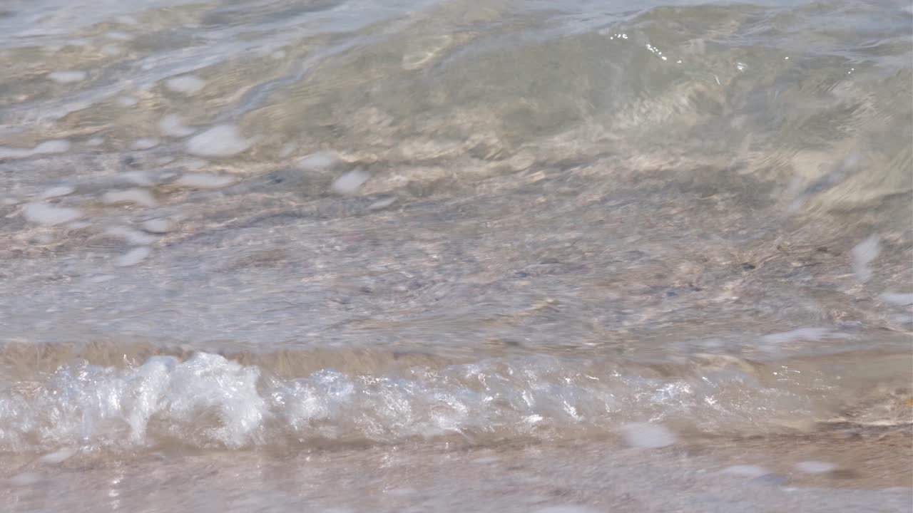 깨끗한 바다가 거품과 함께 모래에 부드럽게 랩핑되는 하얀 모래 해변의 중간 가까이