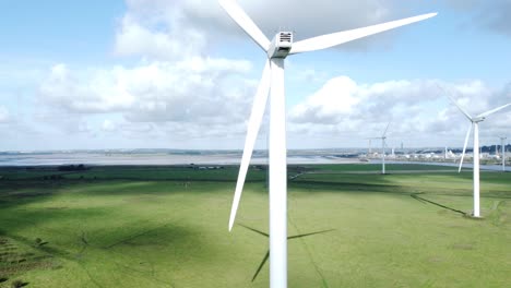 aerial view flying around renewable energy wind farm wind turbines spinning on british countryside rising right