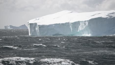 Dramatic-shot-of-waves-crashing-against-huge-iceberg