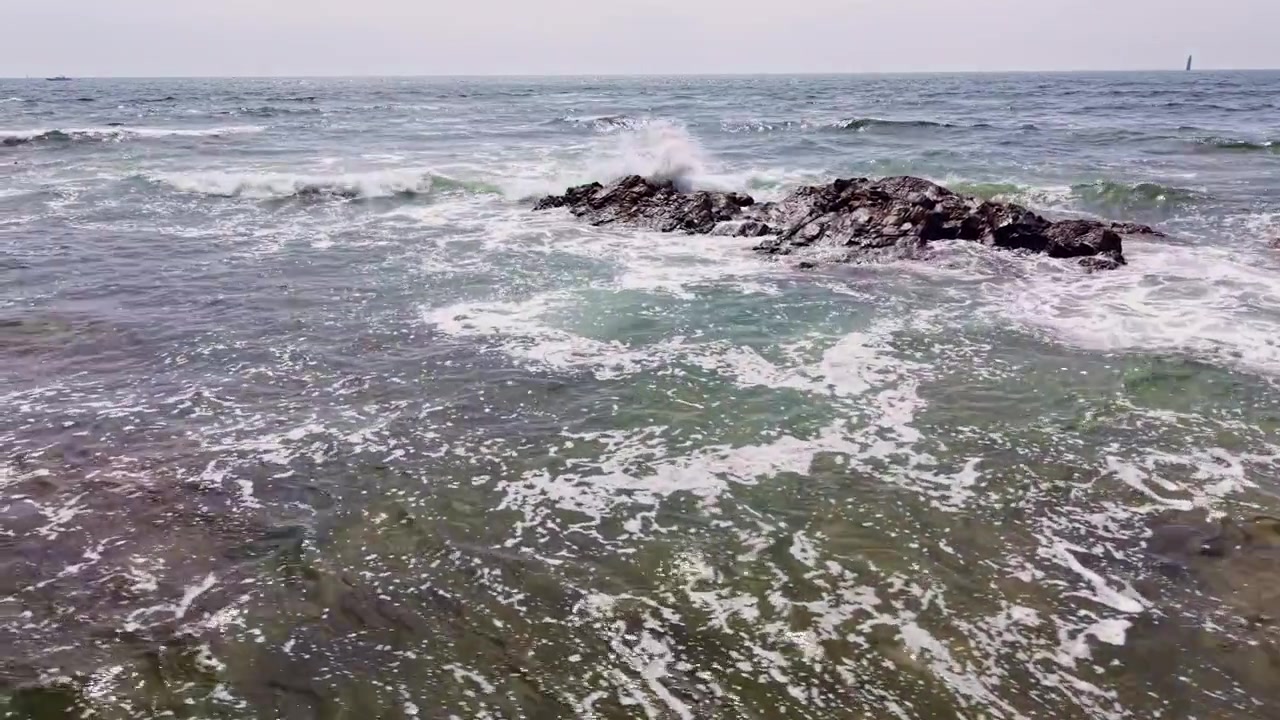 Onde atlantiche si infrangono su formazioni rocciose costiere vicino a Les Sables-d'Olonne, Vandea, Paesi della Loira, Francia, con schiuma delle onde e acqua costiera limpida, ripresa aerea con scorrimento laterale a sinistra del drone