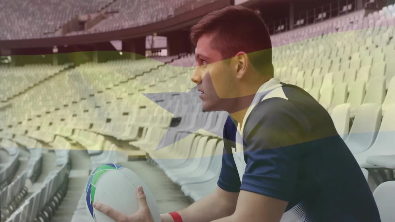 Scena sportiva che ritrae un giocatore di rugby seduto sugli spalti, che si concentra stringendo il pallone e osservando il campo.