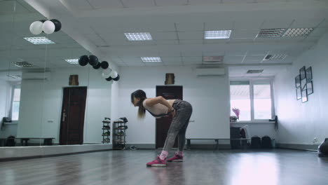 Caucasian-female-dancer-choreographer-doing-warming-up-moves-against-a-big-mirror-wall-in-a-dance-studio