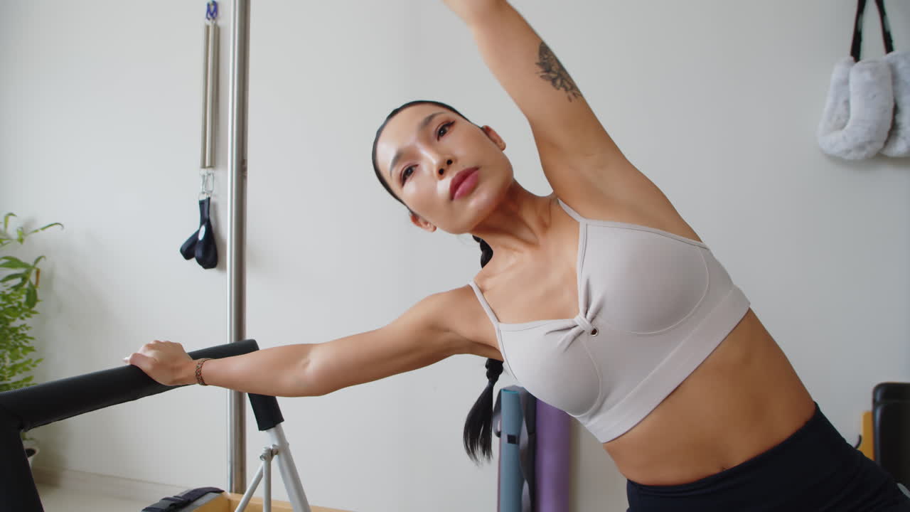 Asian Sportswoman Stretching in Side Bend in Fitness Equipment