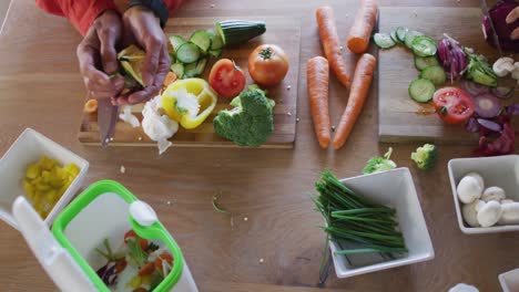 Midsection-of-diverse-couple-cooking-together,-chopping-vegetables-and-cleaning-in-kitchen