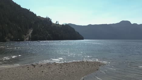 Low-drone-flight-over-beach-reveal-mountains-by-Jervis-inlet-bay,-BC,-Canada