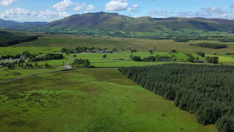 Flying-over-green-fields-towards-distant-Blencathra-mountain-range-on-bright-summer-day