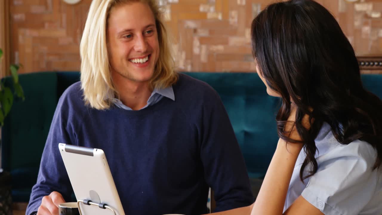 mujer y hombre interactuando entre sí mientras usan una tableta digital