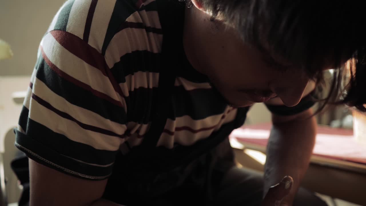 남자 도자기 가 일 하는 동안 도자기 바 에 구부러져 있는 근접적 인 얼굴