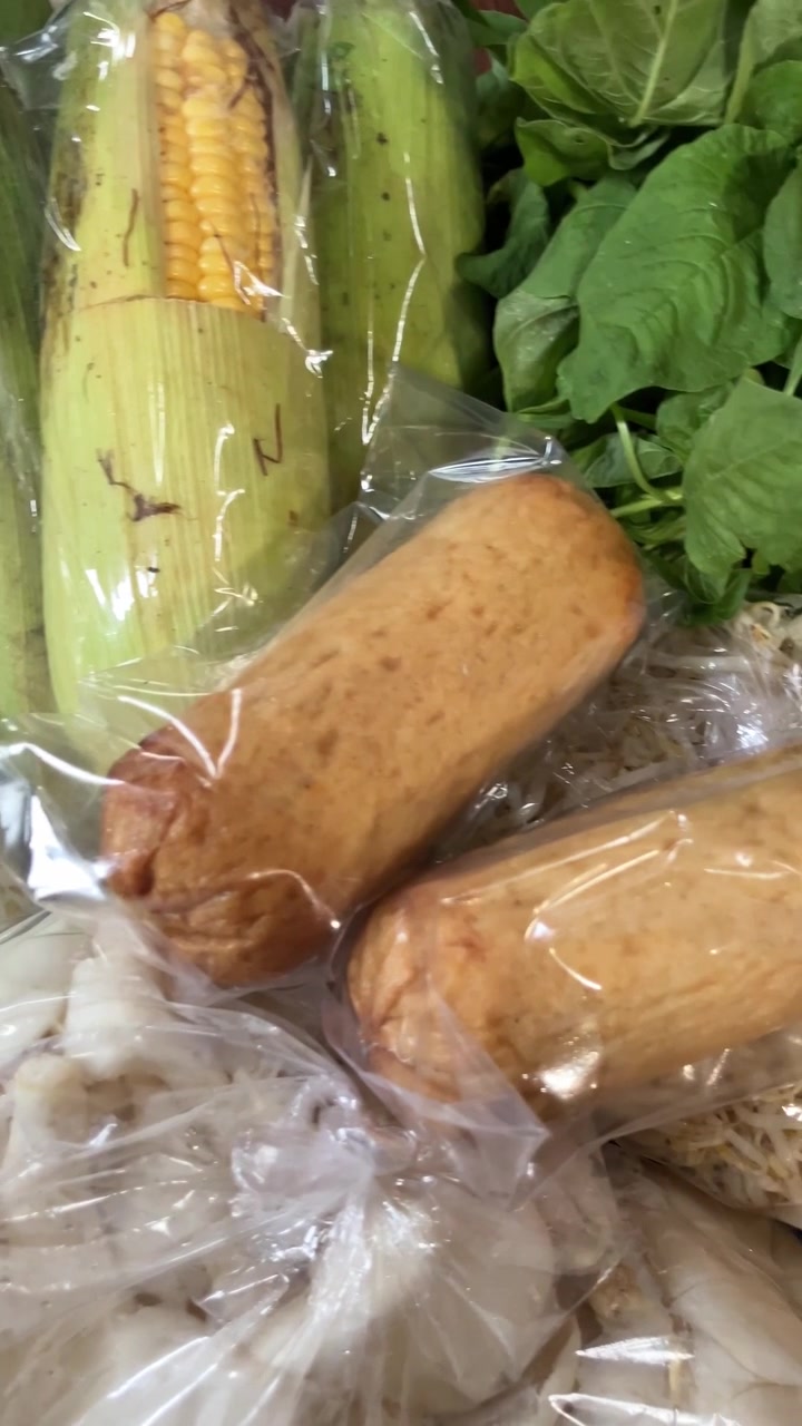 新鮮な野菜、テンペ、スイートコーン、キノコがプラスチックに包まれたクローズアップの縦型動画。小家族の毎日の食事のために伝統的な地元の市場で購入された健康的な生食材