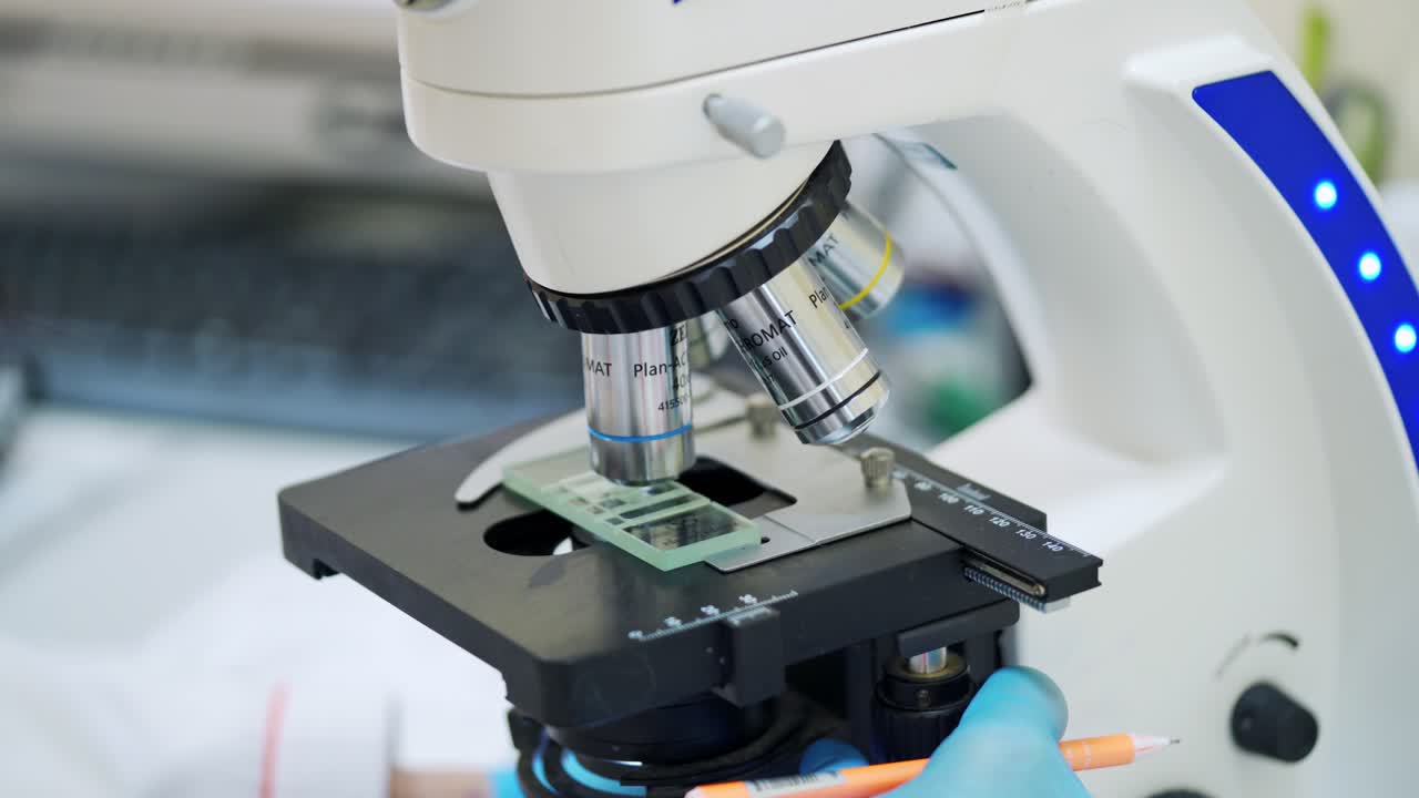 Medical equipment for blood examination. Scientist examining sample, looking into microscope