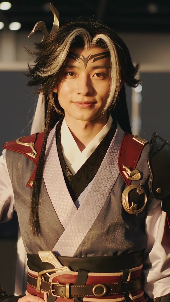 Asian adult male performer holding pose while camera zooming in at expo showcasing costume details