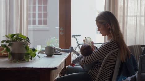 Madre-Feliz-Alimentando-Al-Bebé-Bebiendo-De-Una-Botella-De-Leche-Mamá-Amorosa-Cuidando-Al-Bebé-Disfrutando-De-La-Maternidad-Relajándose-En-Casa