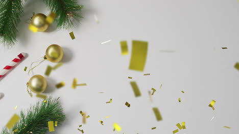 christmas decorations with golden baubles and candy cane over confetti animation