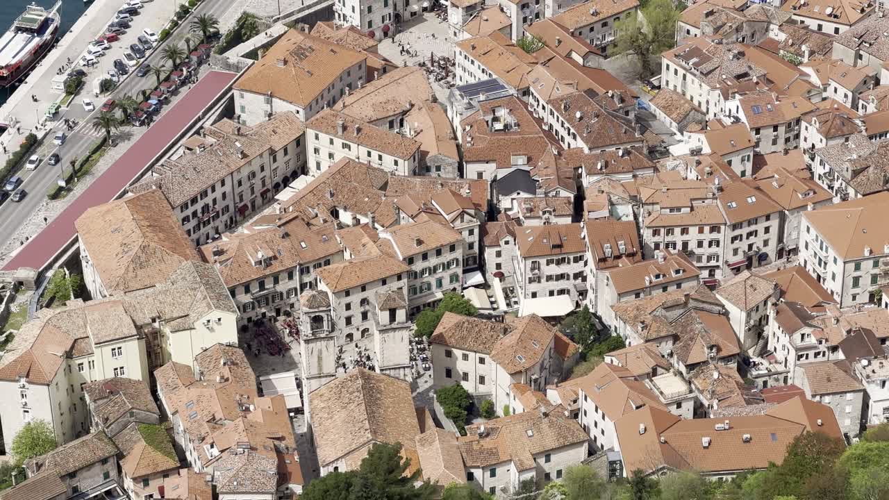 Vista ravvicinata del centro storico di Cattaro che mostra i tetti di tegole arancioni e l'architettura storica, filmata dalla fortezza di Cattaro sopra la città con vista sulla baia di Cattaro in Montenegro