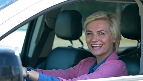 Porträt-Einer-Attraktiven-Geschäftsfrau-An-Einem-Sonnigen-Sommertag,-Die-Hinter-Dem-Lenkrad-Im-Auto-Sitzt-Und-In-Die-Kamera-Lächelt