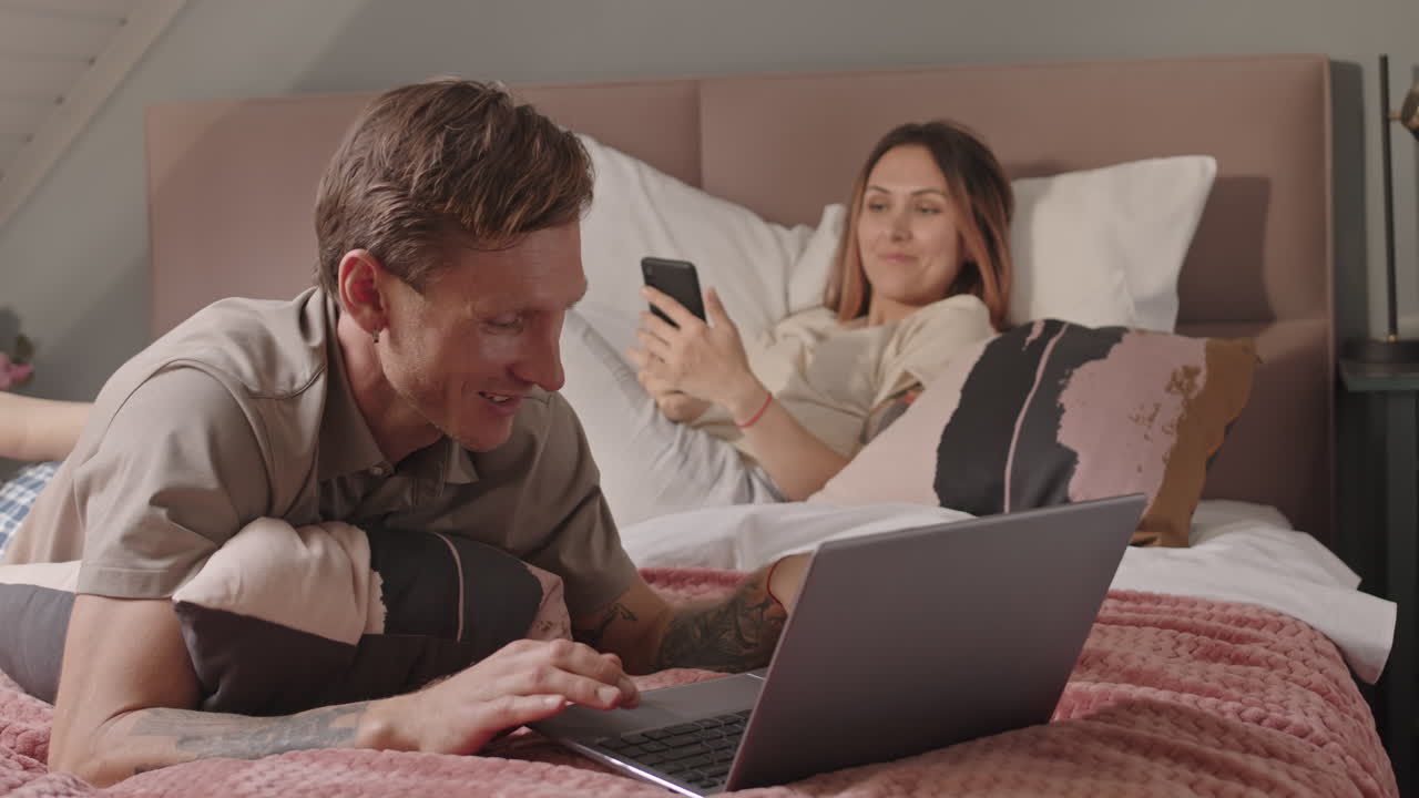 Couple Using Gadgets in Bed