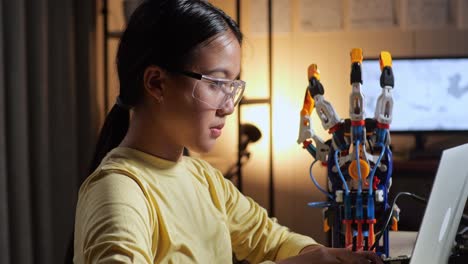 close up of teen asian girl having a headache while working about a cyborg hand on a laptop at home