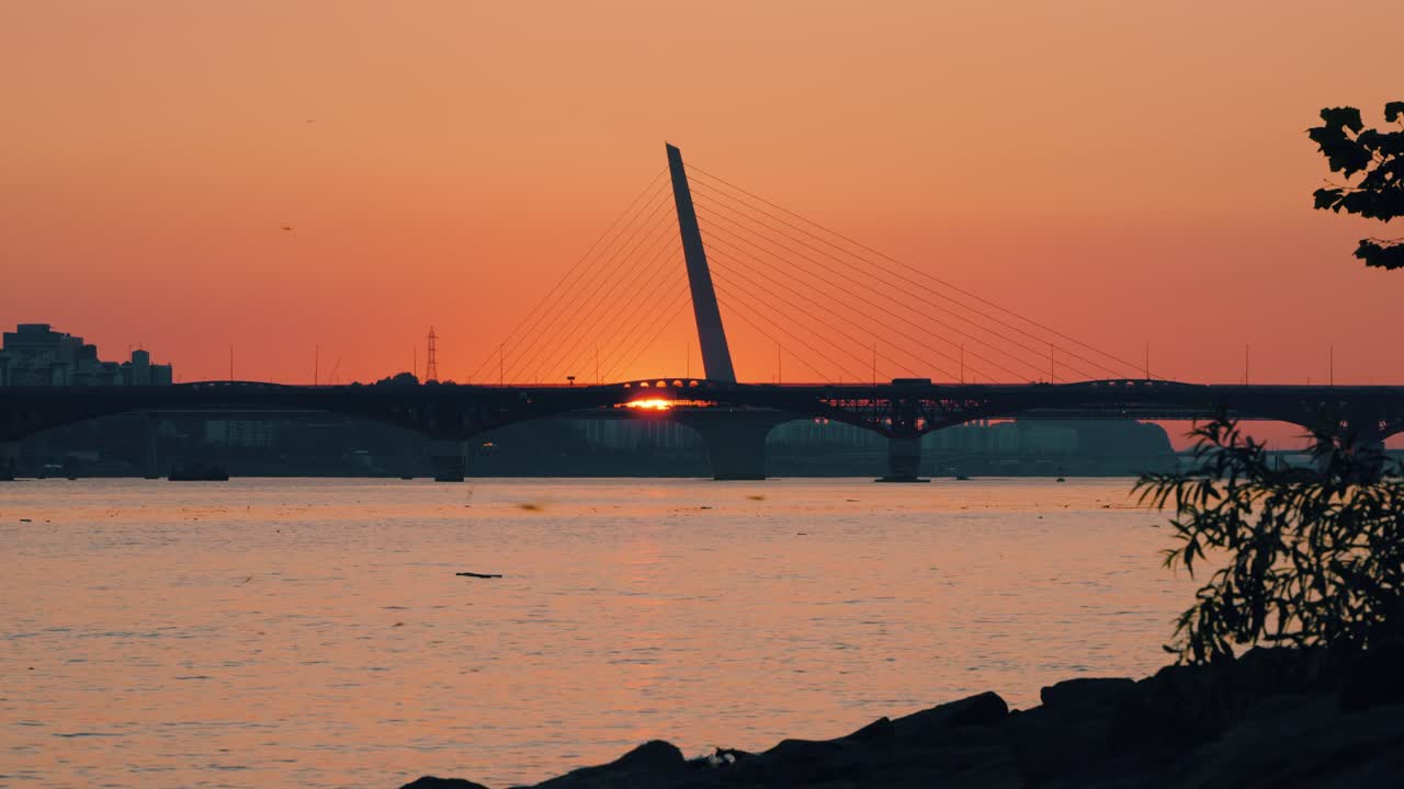 Golden sunset over the Han River as seen from Hangang Park in Seoul, with silhouettes of Seongsan Bridge and World Cup Bridge against the glowing pink sky