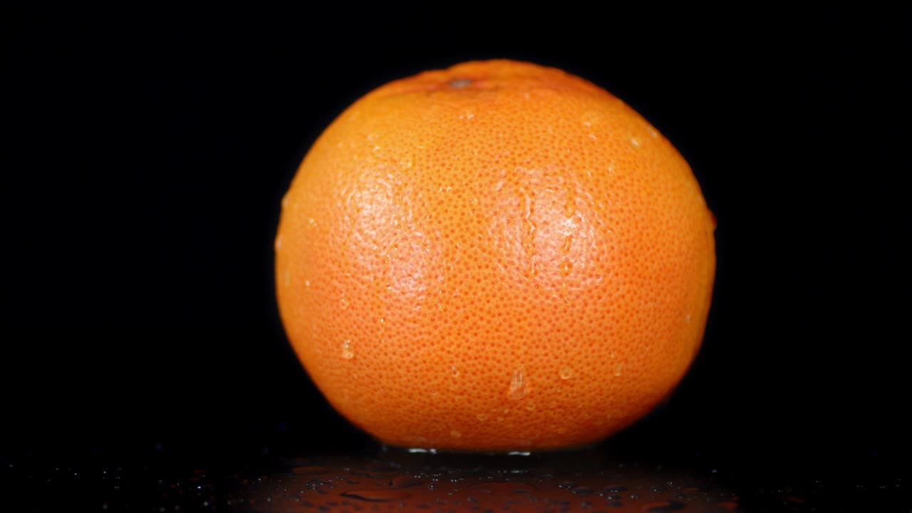 un pomelo entero cayendo gotas de agua.