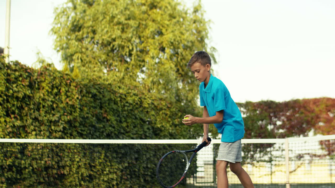 Teen Boy Throwing Ball On The Floor And Then Hitting With Racket During Training On Outdoor Tennis Court On A Summer Day 1
