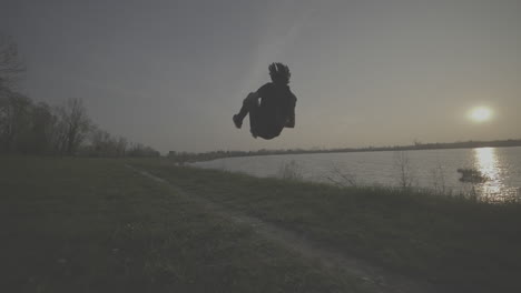 man dancing at sunset by river
