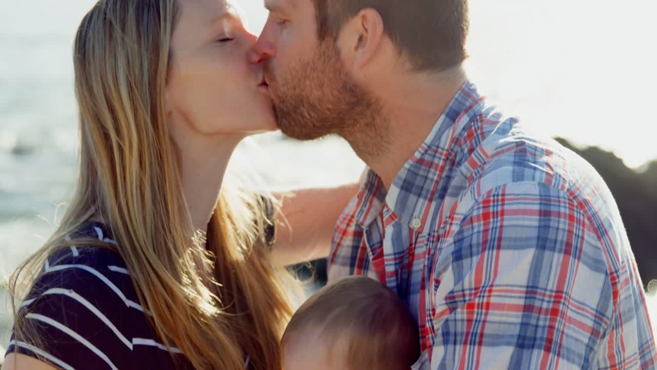 vista laterale di genitori caucasici adulti che si baciano in spiaggia in una giornata di sole 4k