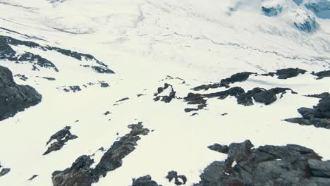 Person-Sitzt-Auf-Bergrücken-Auf-Fliegender-FPV-Drohne-In-Majestätischer-Winterlandschaft