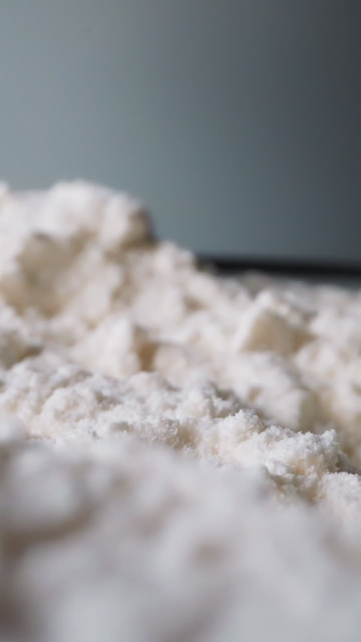 Unsifted flour lies spilled on table against dark grey wall. Raw grain culinary ingredient for baking. Pile of clean wheat bran in kitchen macro