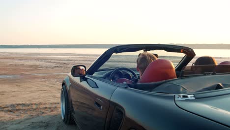 young happy couple driving in cabriolet during sunset, slow motion