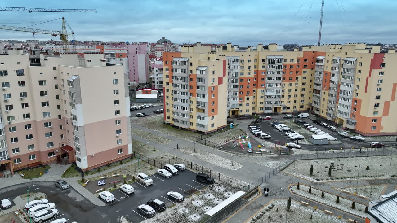 Newly constructed residential area of blocks of flats. Flying a drone over the modern district with high houses, roads and cars. Cityscape at the backdrop.