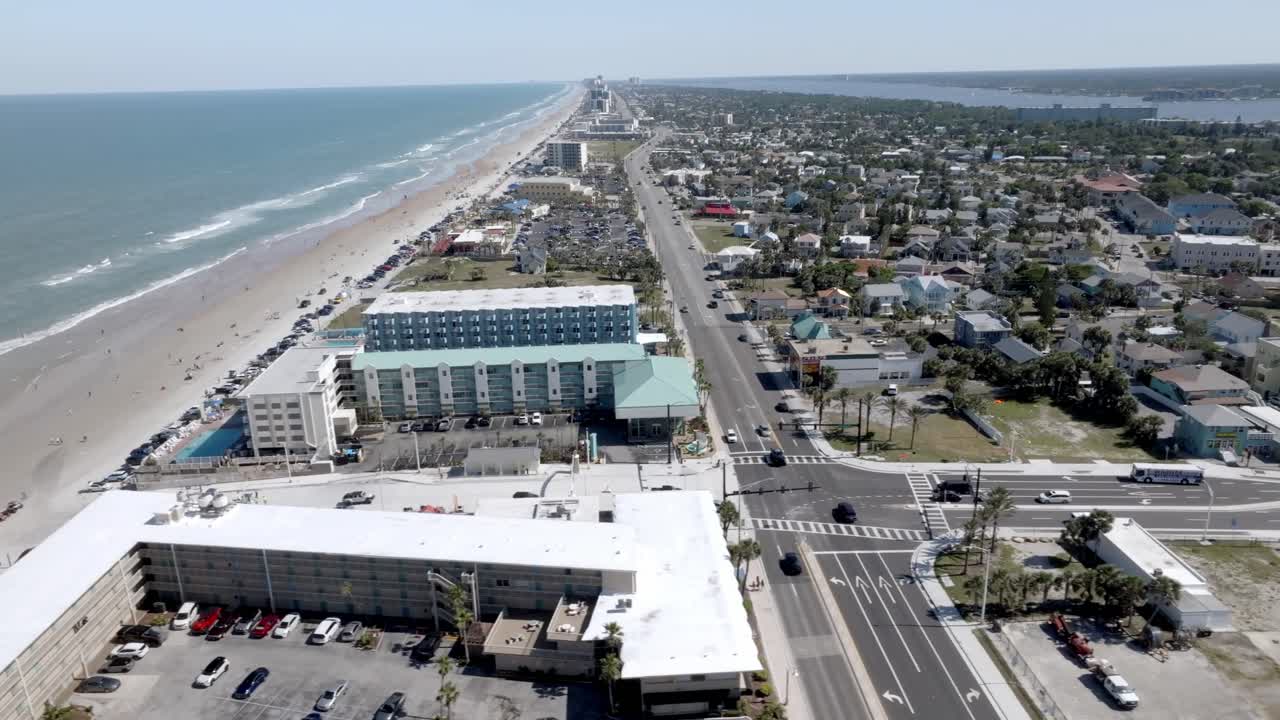Daytona Beach, Florida with waves from the Atlantic Ocean, vehicles, hotels and people on the beach with drone video sideways.