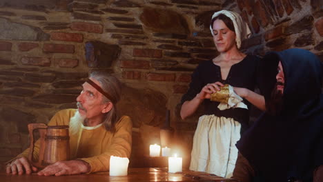 man keeps eyes on new guest while disinterested maid cleans mug in pub. constant visitors and sarcastic servant prepare for troubles from newbie in medieval pub