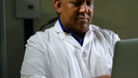 front view of mature male worker using laptop in glass factory 4k