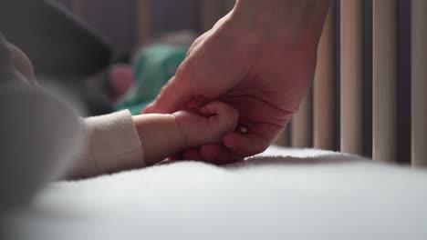 woman gently touch and hold sleeping newborn baby hand, mother love and care