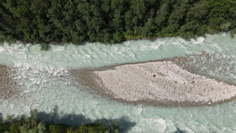 strong current of water in the mountain river surrounded by green forest on a sunny day