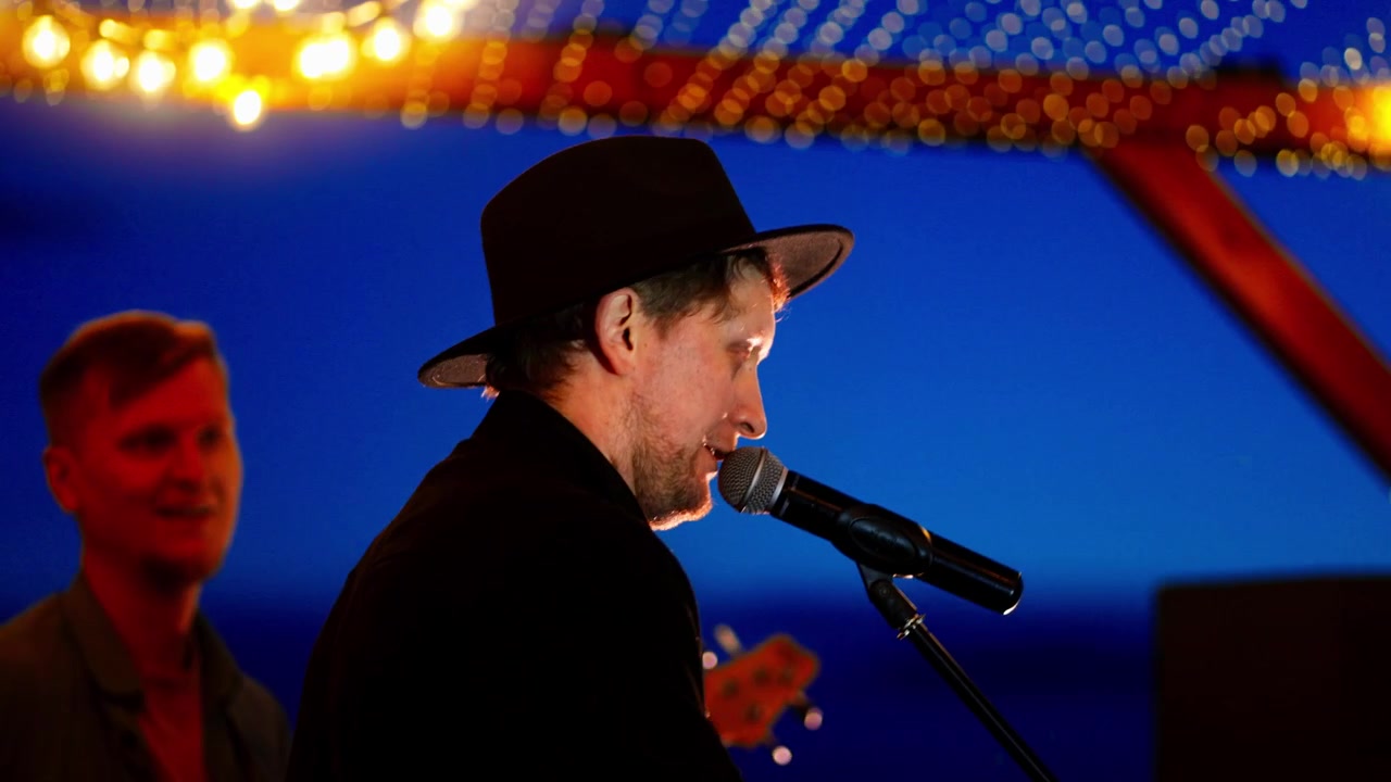 Musikere spiller livemusikk på en utendørsscene i skumringen