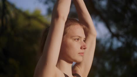 chica caucásica realizando pose de asana de yoga de pie al amanecer, afuera en el bosque