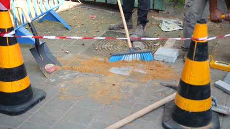 Worker-cleaning-the-road-from-sawdust-with-a-broom-after-a-maintenance-job