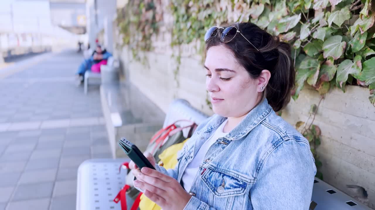 A Traveler Using Her Smartphone at an Outdoor Platform at a train station platform