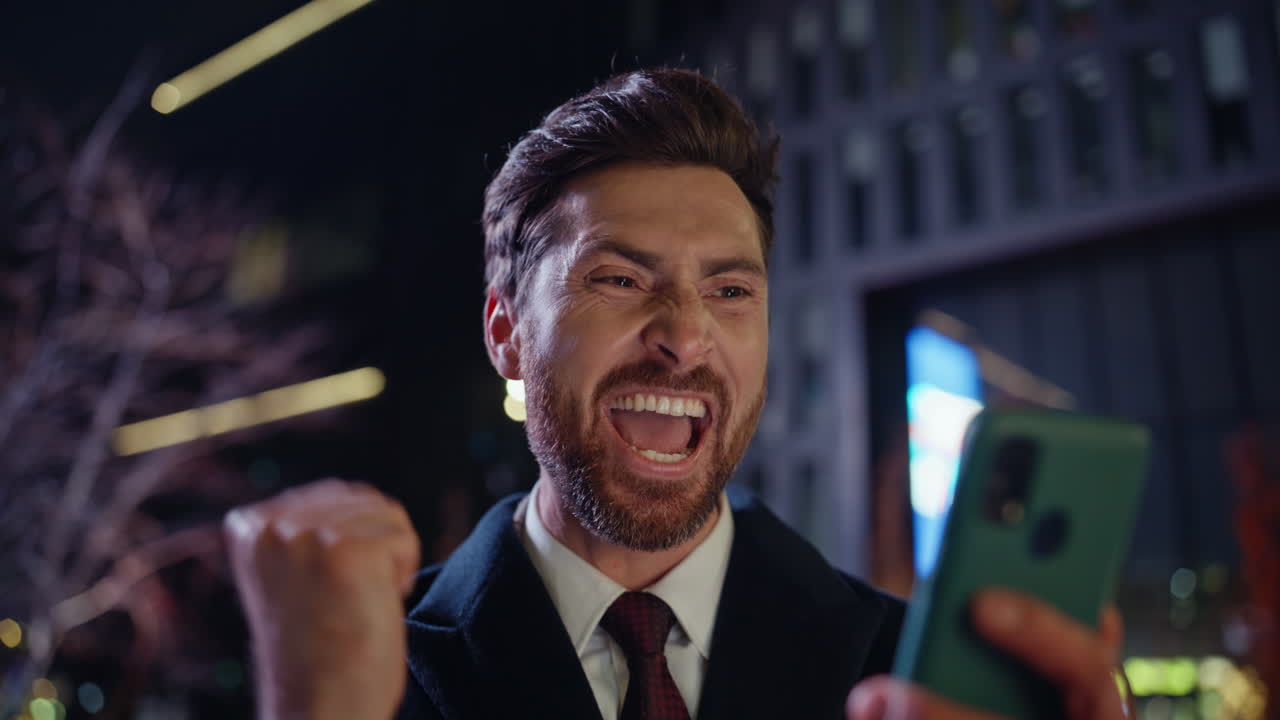 Evening winner reading mobile phone screen dark square portrait. Man rejoicing