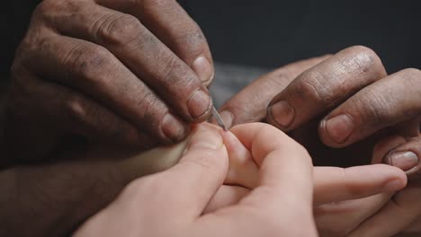 hand removing splinter from another's hand, labor in the workshop - closeup