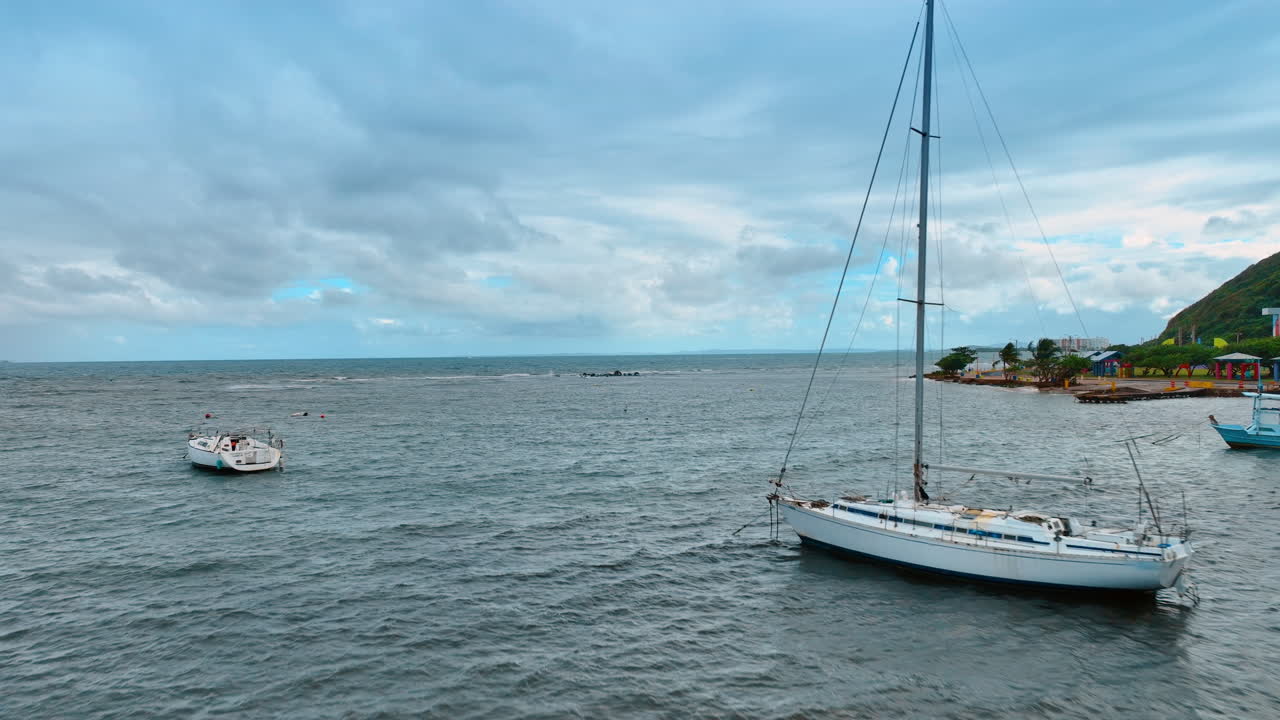 Voo sobre paisagem aquática cinzenta e turbulenta em dia nublado. Barcos estão na paisagem marinha na costa de Porto Rico. Nuvens dramáticas cobrem o céu em dia de vento.