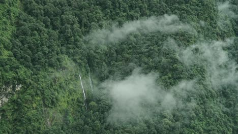 aerial view of waterfalls in mountains forest in clouds, beautiful green nature shot of elevated aerial view of waterfalls in himalaya mountains in nepal in lush greenery forest scenery