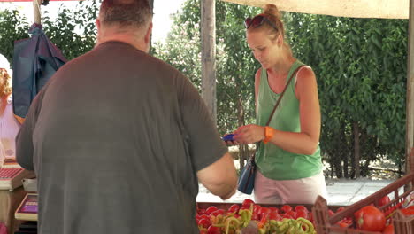 mujer pagando por verduras en el mercado