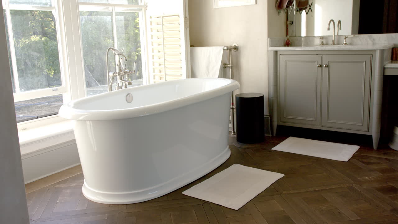 Freestanding bathtub in modern bathroom with large window, creating serene atmosphere