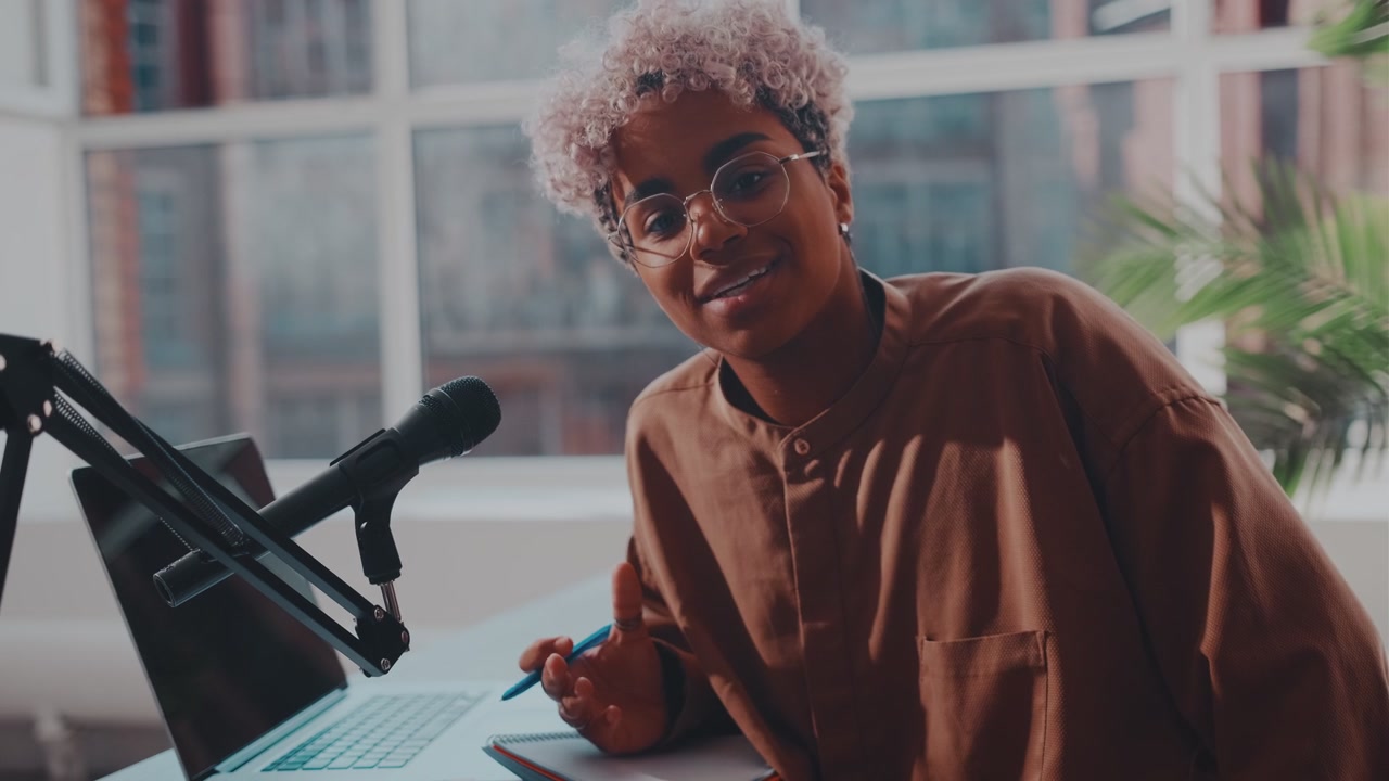 African woman sitting in front of camera recording video with podcast microphone